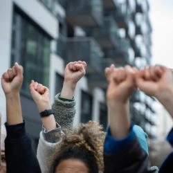 várias mãos levantadas e fechadas em sinal de luta